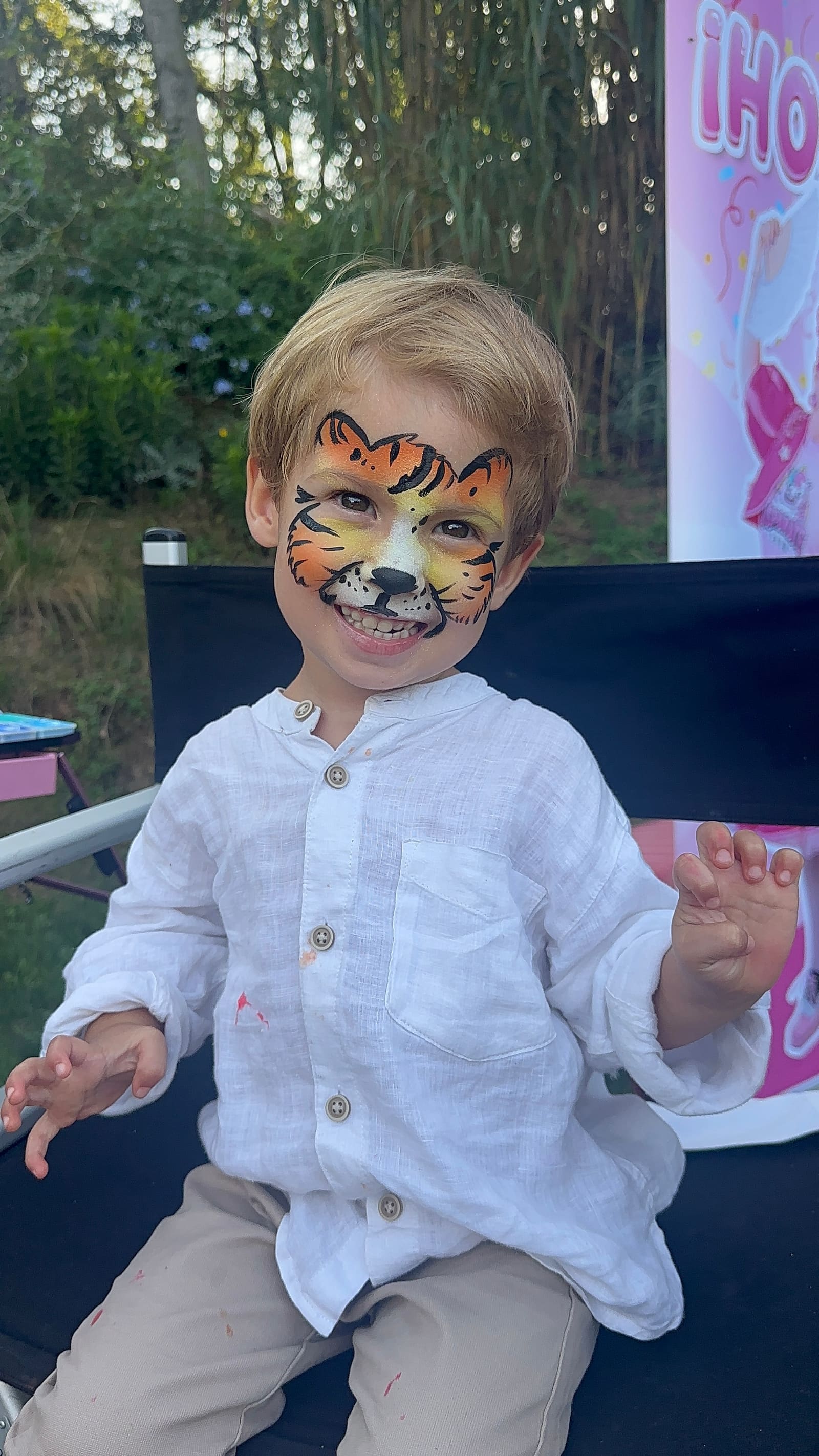 Un niño con la cara pintada de tigre, sentado en la silla del corner