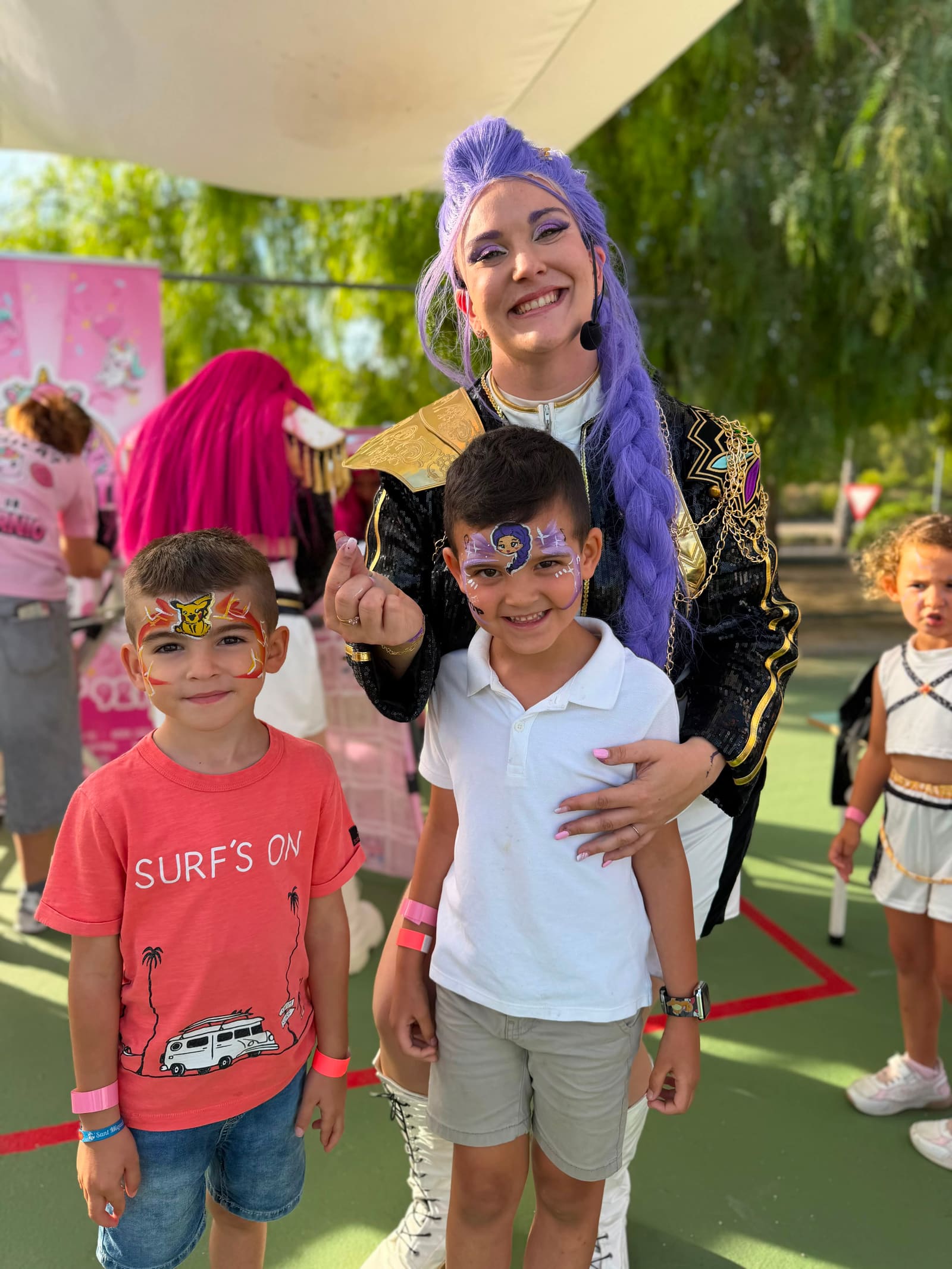 A K-Pop artist with a lilac braid poses with two freshly made-up boys