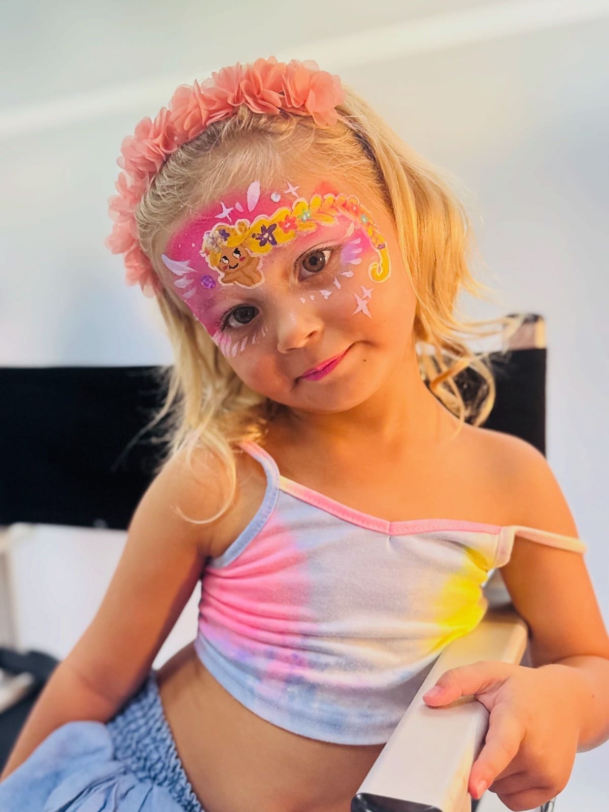 A girl smiles with flowers and glitter painted on her face