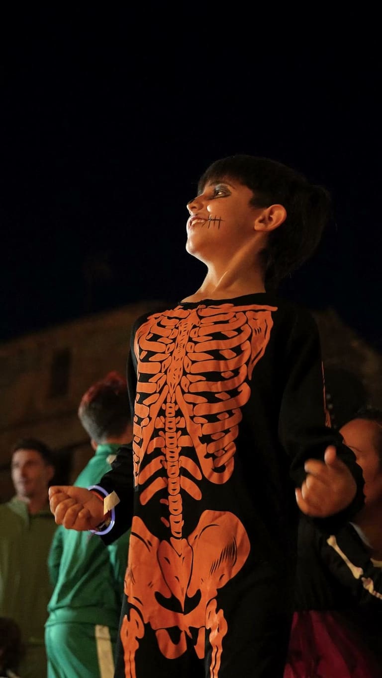 A boy dressed as a skeleton dances in front of the stage