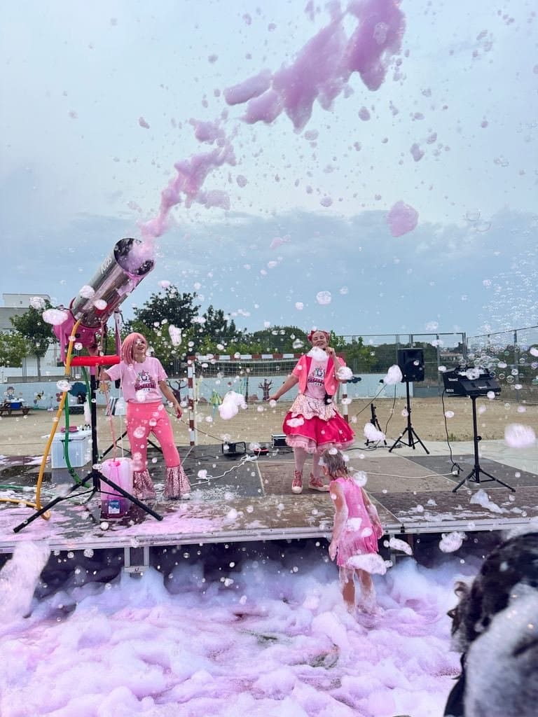 The cannon fires a jet of pink foam over the floor while the host dances on stage