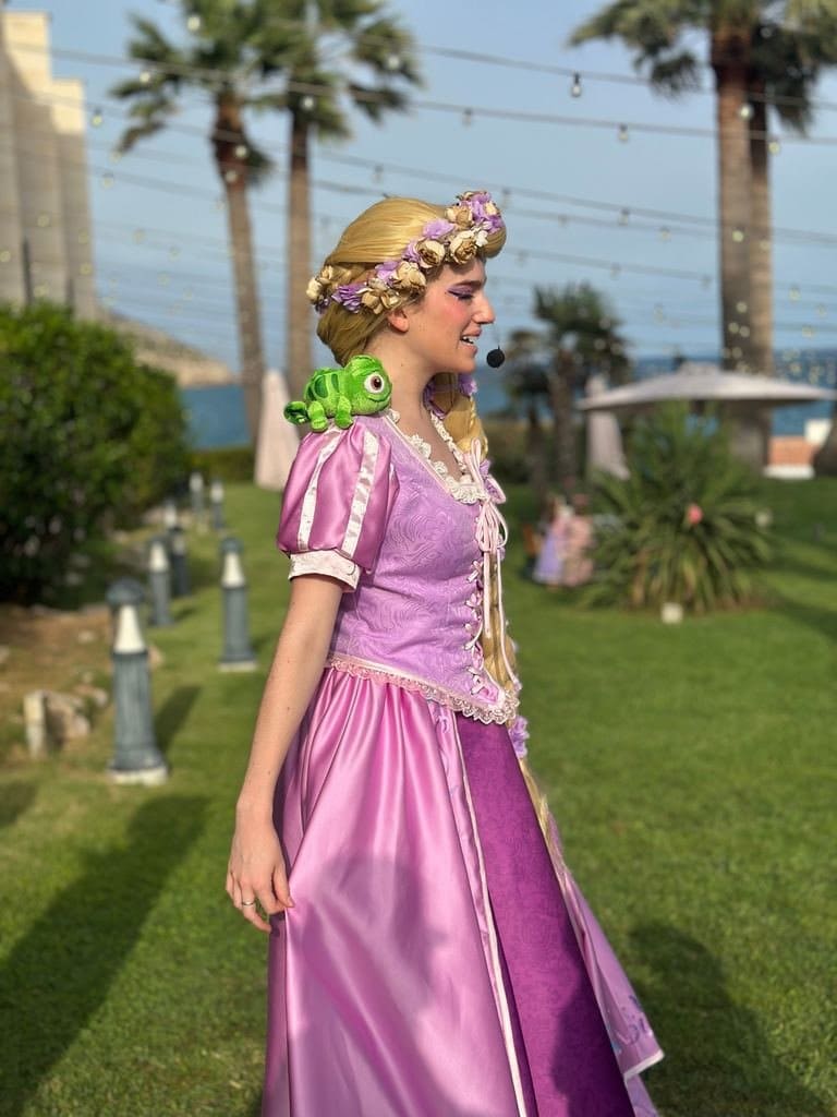 Rapunzel full length, in profile, among palm trees with the sea behind her