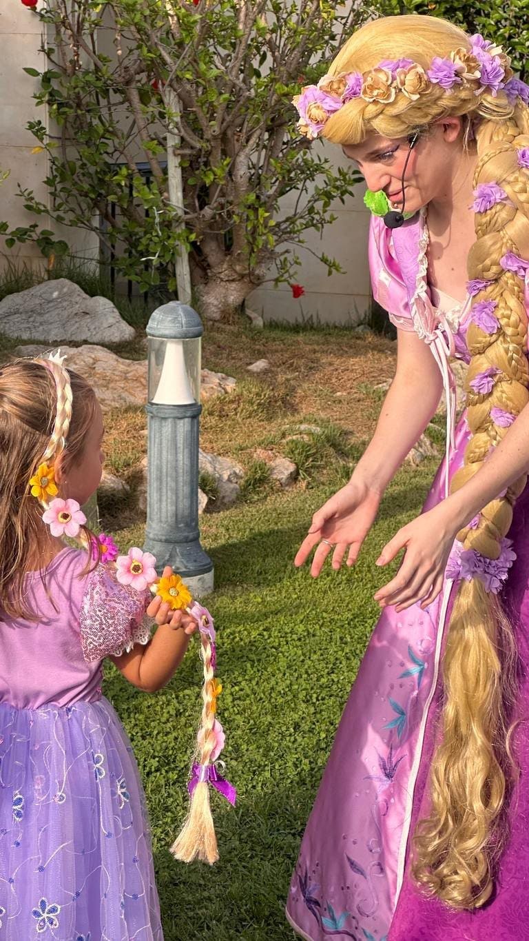 Rapunzel hands the end of her braid to a little girl