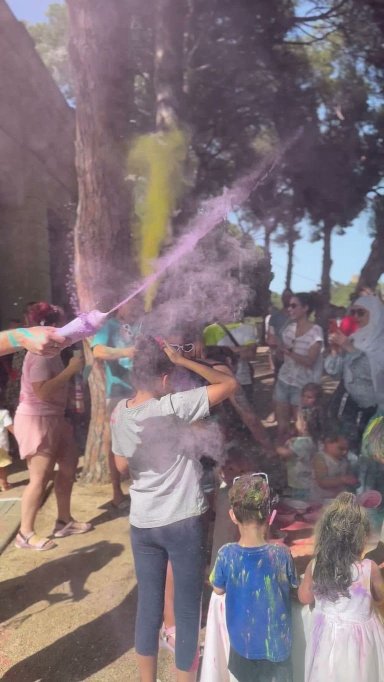 A burst of purple powder in the air, above the crowd