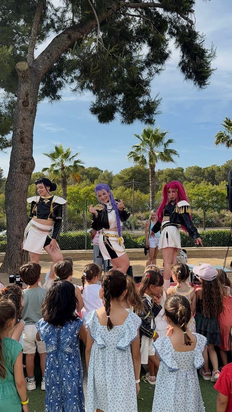 The three performers, now in black jackets and white skirts after the costume change, dance with their backs to the audience
